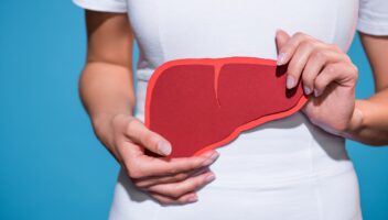 cropped shot of woman holding paper crafted liver in hands on blue background